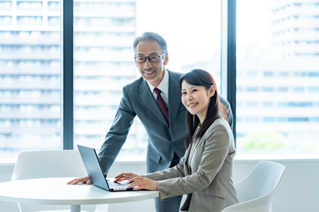 経理担当者と情報システム担当者が打ち合わせをする様子