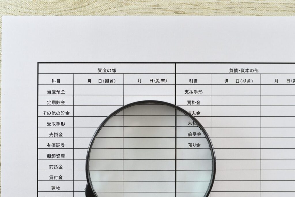 虫眼鏡で帳簿の数字を確認するイメージ