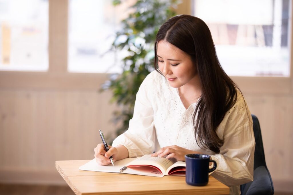 ノートに書き込みながら勉強する女性