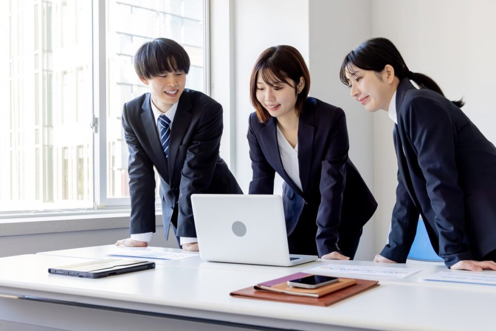 ノートパソコンを囲んで打ち合わせをする社員