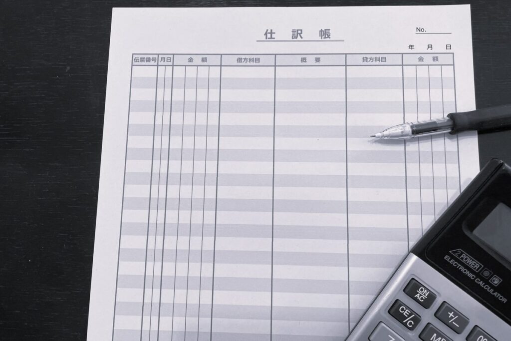 仕訳帳と電卓で仕訳を確認する様子