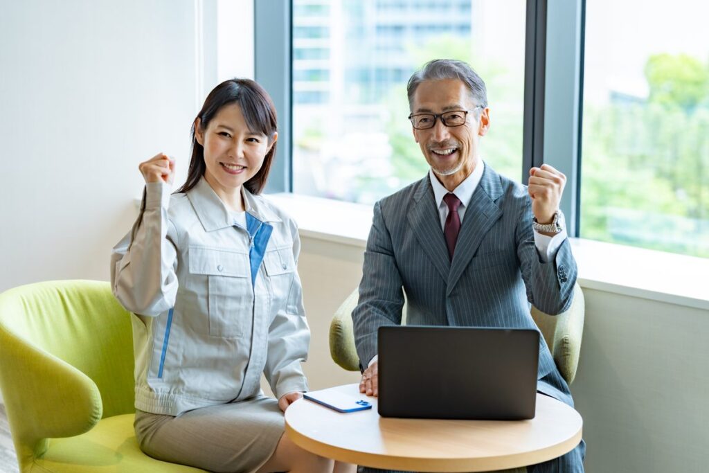 ノートパソコンの前で成果を喜ぶ2人