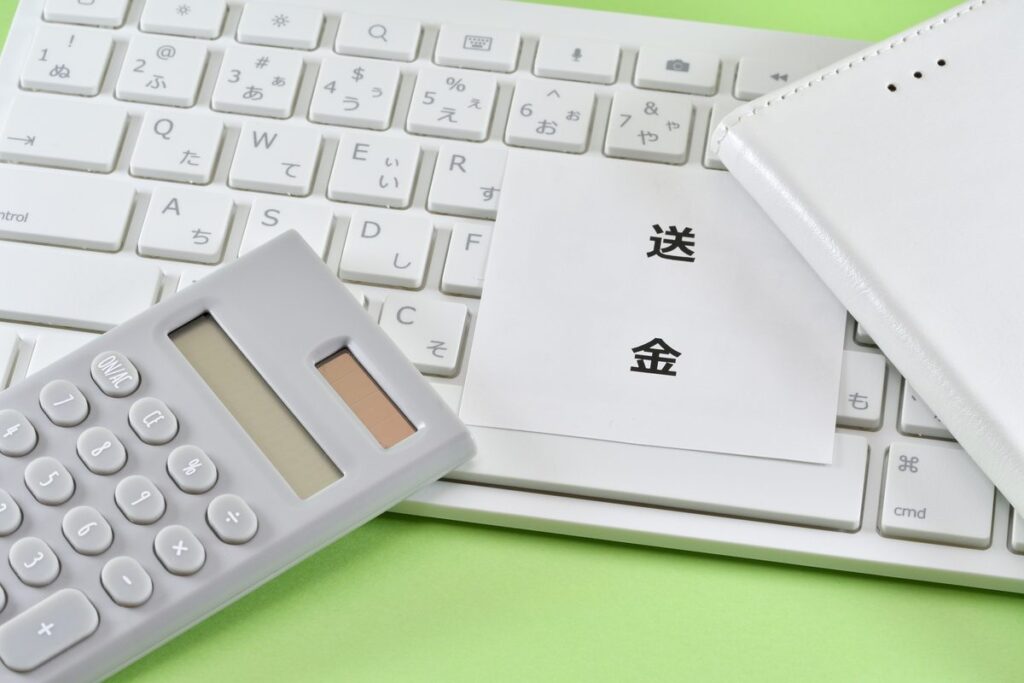 キーボードと電卓の横に置かれた送金メモ