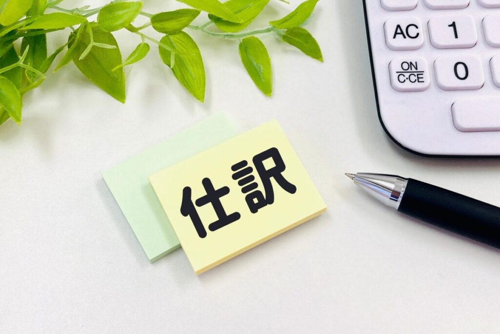 「仕訳」と書かれた付箋とペン