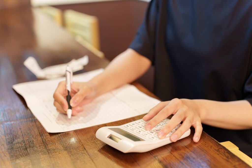 電卓で計算しながら帳簿に記入する手元
