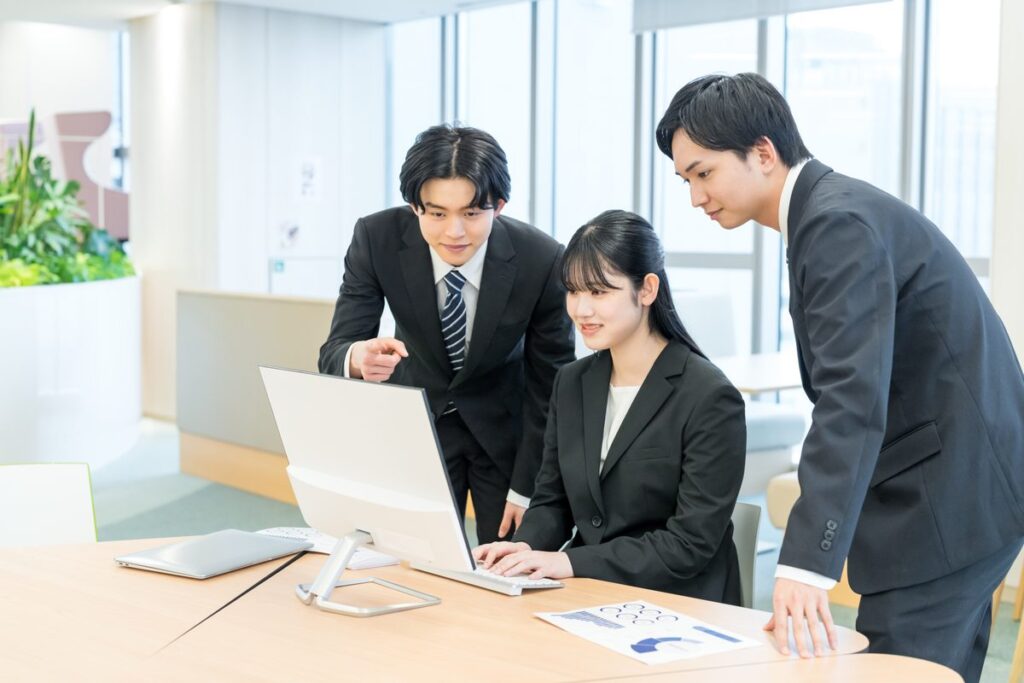 オフィスでパソコンを囲んで打ち合わせをするチーム