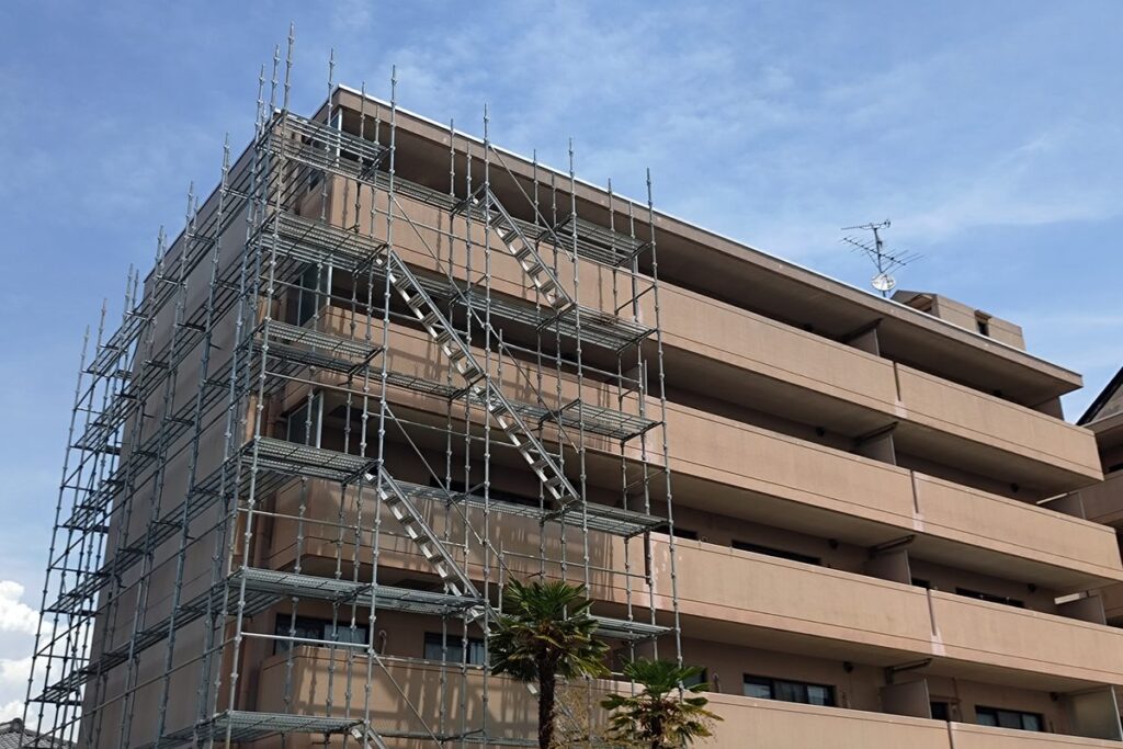 足場を組んで外壁を改修するマンション