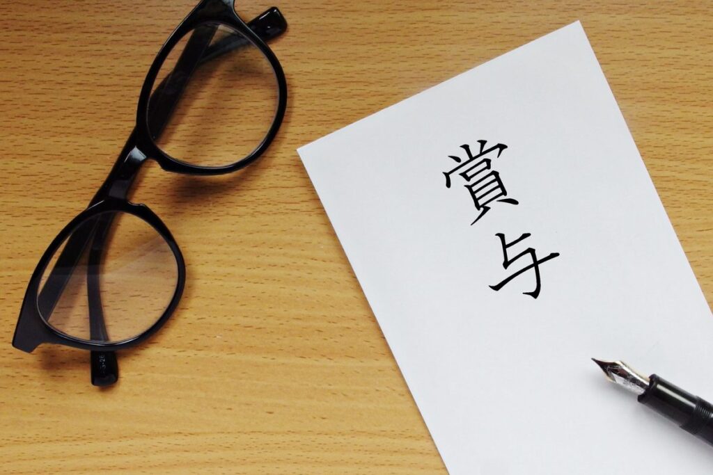 「賞与」と書かれた紙と眼鏡