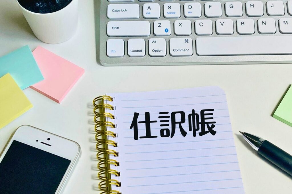 「仕訳帳」と書かれたノート
