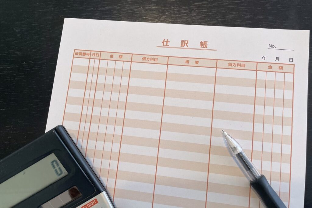 帳簿と電卓で仕訳を確認するイメージ