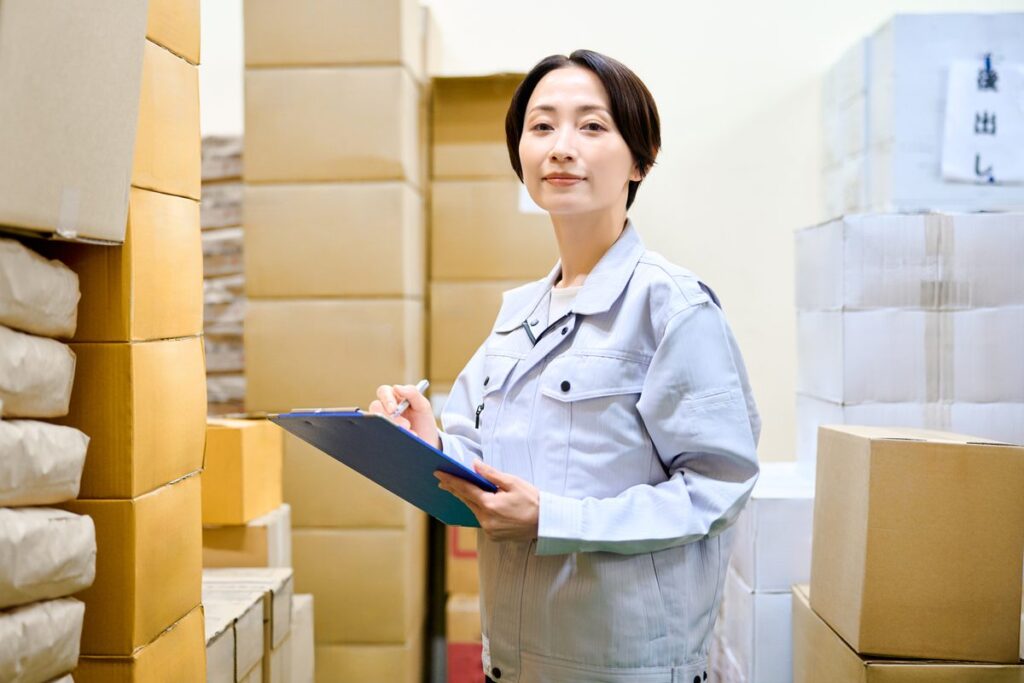 倉庫でクリップボードを持ち在庫を確認する担当者