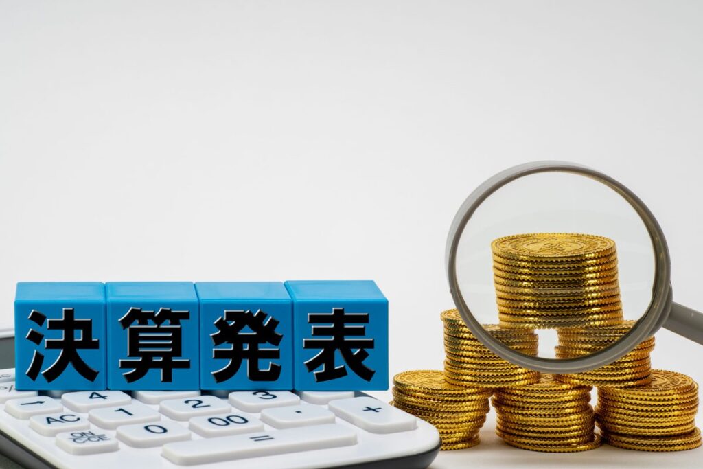 「決算発表」の文字と硬貨・虫眼鏡