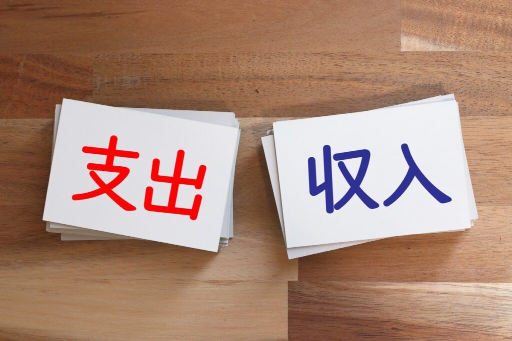 電卓と収入・支出のカードで損益を計算するイメージ