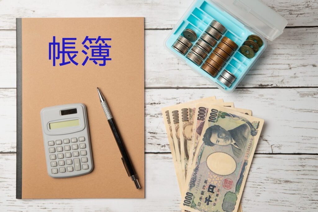 帳簿と電卓で仕訳を確認するイメージ