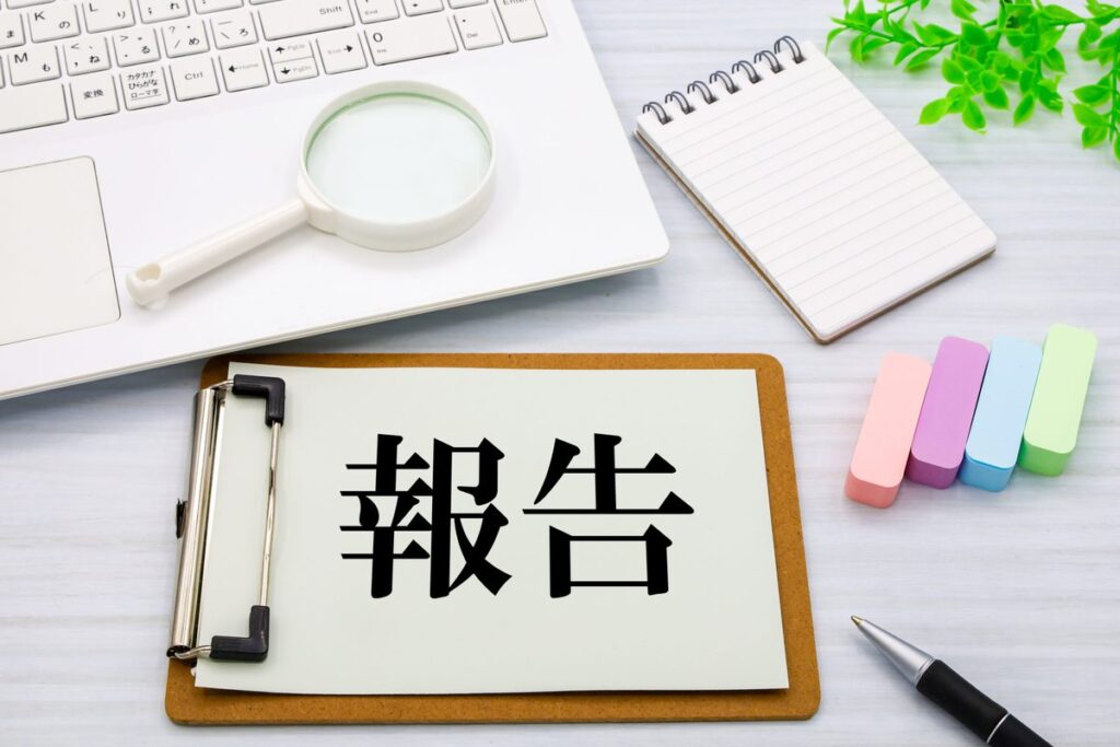 報告と書かれたクリップボードと虫眼鏡のイメージ