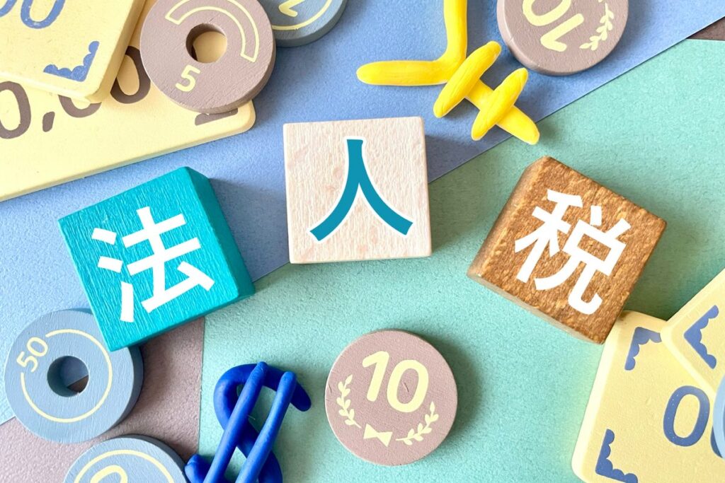 「法人税」の文字ブロックと硬貨