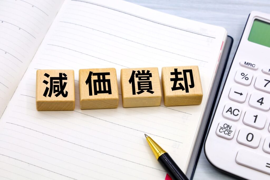 「減価償却」の文字ブロックと電卓